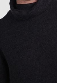 Maglione a collo alto nero realizzato in tessuto morbido e testurizzato. Presenta un colletto e un corpo a coste, con una silhouette aderente e un design minimalista.
