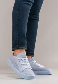 Jasnoniebieskie trampki z teksturowanym siateczkowym cholewką, płaskimi sznurówkami i zaokrąglonym noskiem. Podeszwa jest płaska i solidna, zaprojektowana do codziennego noszenia.