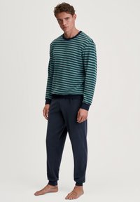 Gestreifter Pullover in Petrol und Navy mit Rundhalsausschnitt, kombiniert mit navy Jogginghosen mit elastischen Bündchen. Baumwollstoff mit weicher Textur.