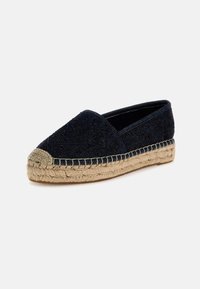 Navy blue espadrille with textured upper, rounded toe, jute midsole, and contrasting beige stitching along the edge. Flat rubber sole.