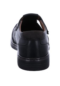 Black leather shoe with a rounded back, textured suede heel accent, and stitched details on the sole. Minimalistic design.