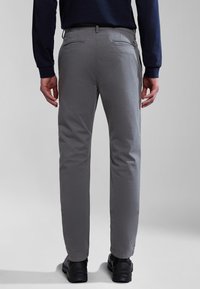 Pantaloni di cotone grigi con un design a gamba dritta, dotati di due tasche posteriori e una texture sottile. Indossati con scarpe nere.