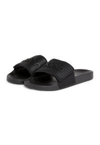 Mustad mustkaded, tekstureeritud rihmaga, millel on reliefne "Calvin Klein" logo. Sile tald ja pehme ülemine materjal. Lame disain igapäevaseks kandmiseks.