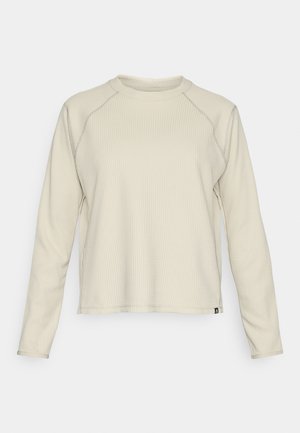 Lys beige langermet topp med en teksturert, ribbet design. Har raglan-ermer og en rund halsutskjæring. Diskret merkevarelogo nederst.