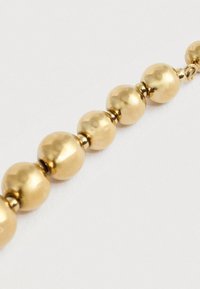 Χρυσή βραχιόλι με χάντρες που διαθέτει στρογγυλές, γυαλιστερές χάντρες διαφόρων μεγεθών, με λεία υφή και εναλλασσόμενους μικρούς διαχωριστές.