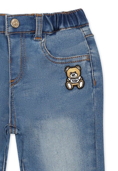 Jeans in denim con vita elasticizzata, di colore azzurro chiaro, dotati di tasche e con un orsetto di peluche marrone ricamato sulla tasca frontale.
