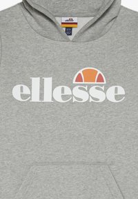Sudadera gris con bolsillo canguro y capucha con cordón. Presenta un logo blanco de "ellesse" y un gráfico de semicírculo colorido.