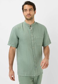 Korte mouwen, mintgroen shirt met een mandarinelijfje, knopen aan de voorkant en een enkele borstzak. Gemaakt van een gestructureerde stof.