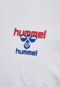 Czerwono-niebieskie logo tekstowe „hummel” z stylizowaną grafiką trzmiela na białym tle z tkaniny.