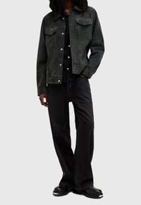 Svart mockajacka med två bröstfickor, i kombination med svarta denimbyxor och kraftiga svarta stövlar. Har silverknappar och sömnadsdetaljer.