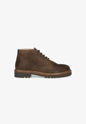 Brown leather ankle boots with a rounded toe, six eyelets, and rugged rubber sole featuring deep traction grooves. Stitch detailing on the side.