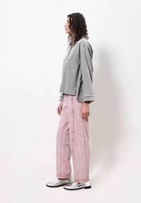 Graues Denim-Hemd mit einer Tasche, kombiniert mit hellrosa weit geschnittenen Hosen und silbernen Loafers, mit einem lässigen Schnitt und bestickten Akzenten.