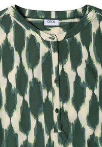 Blouse à motifs verts et beiges avec un col rond et quatre boutons verts au centre devant, étiquette indiquant CECIL à l'intérieur du col.