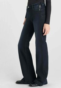 Donkerblauwe flare jeans van denim, met een standaard vijf-pocket ontwerp en een enkele decoratieve patch op de achterzak.