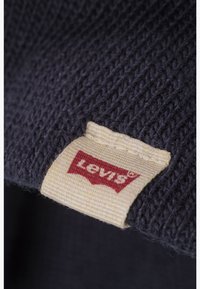Marine strikstof med en tekstureret overflade, med et tan stofmærke med en rød "Levi's" logo i kanten.