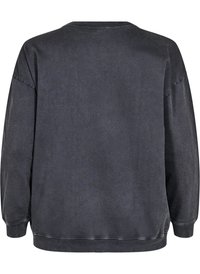 Felpa nera oversize con scollo rotondo, maniche lunghe, polsini a costine e una texture leggermente vissuta. Nessun motivo o accessorio visibile.
