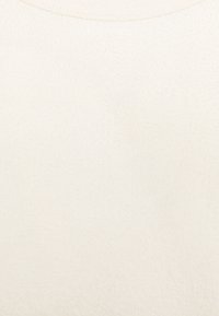 Maglione color crema realizzato in un morbido tessuto testurizzato, con scollatura rotonda e sottili variazioni tonali su tutta la superficie.