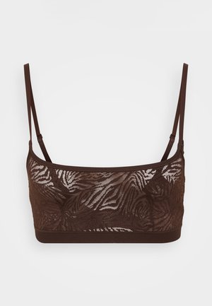 Brūns mežģīņu bralette ar zebras rakstu, ar regulējamām siksnām un mīkstu apakšmalu. Materiāls izskatās puscaurspīdīgs un teksturēts.