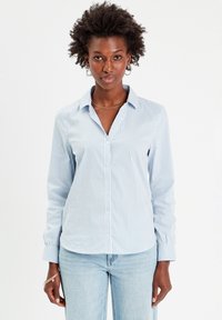 Chemise à boutons à rayures bleu clair et blanche, avec un col, des manches longues et une finition en tissu lisse. Présente une coupe normale et des boutons sur le devant.