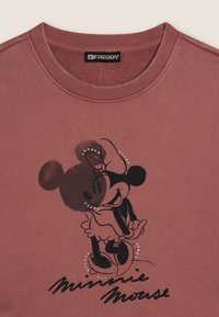 Sudadera de algodón color rosa polvo con un dibujo de Minnie Mouse en negro con un lazo, detalles brillantes y el texto "Minnie Mouse" en negro.
