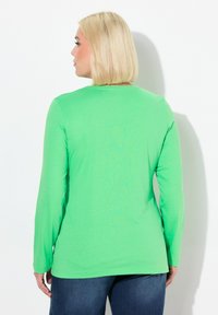 Langärmliges grünes Hemd aus leichtem Stoff, mit einem schlichten runden Ausschnitt und einem glatten, leicht taillierten Design.