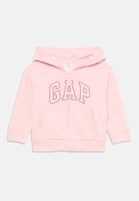 Haut à capuche pour tout-petits rose clair avec fermeture éclair à l'avant, poche kangourou et logo "GAP" en lettres roses en contour sur la poitrine.