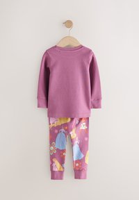 Lilla langærmet skjorte med rund hals, kombineret med lilla leggings med et farverigt mønster af tegneseriefigurer og blomsterdetaljer.