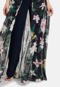 Kimono avec superposition florale en tissu transparent, à fond noir, avec de grandes fleurs roses et blanches, et une couche inférieure sombre unie.