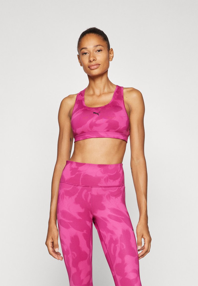 Sujetador deportivo rosa y leggings de cintura alta con un patrón de camuflaje. El material es elástico y de textura suave. Presenta el logo en el sujetador.