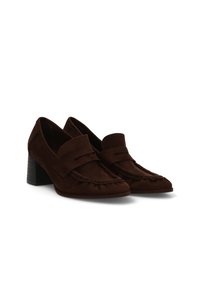 Un par de mocasines de ante marrón oscuro con tacones bajos y un diseño de puntera de mocasín cosido sobre un fondo blanco.