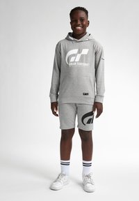 Hoodie gris avec le logo blanc "Gran Turismo", associé à un short assorti arborant un grand logo noir. Accentué par des chaussettes rayées blanches et noires.