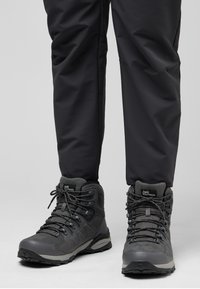 Scarpe da trekking grigie con mesh testurizzato e materiali sintetici, dotate di caviglie rinforzate, lacci robusti e una suola stampata per una migliore aderenza.