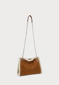 Barna velúr kézi táska krém színű gyapjúbéléses díszítéssel, láncos pánttal és fém kiegészítőkkel. A táska puha tapintású és struktúrált formájú.