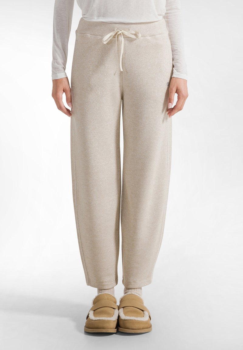 Beige, gestructureerde joggers met een trekkoord in de taille, een relaxed fit en geribde manchetten. Gecombineerd met tan kleurige, met bont gevoerde sloffen en lichtgekleurde sokken.