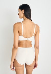 Beige bra and high-waisted brief set, smooth fabric, adjustable straps, hook closure at back, minimal seams, seamless design.