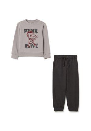 Felpa grigia con la scritta "PUNK" e "ALIVE", caratterizzata da un riccio in stile cartone animato. Pantaloni joggers grigi scuri con vita elasticizzata e fondo a costine.