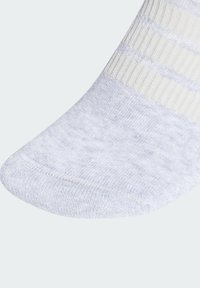 Calcetín gris claro con un patrón y textura suave, presenta un diseño de rayas claras en contraste y una sección reforzada en la punta.