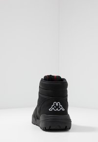 Svart ankelboot med vadderad krage, texturerat syntetmaterial, röd innersula och vit Kappa-logotyp på hälen. Robust gummisula.
