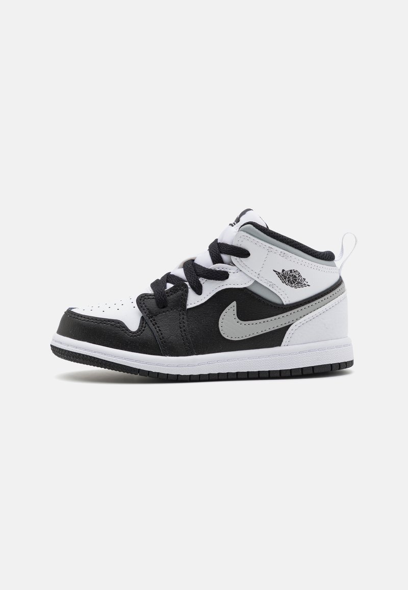 Basket montante noire, blanche et grise avec des lacets noirs, un logo Nike swoosh et un logo Air Jordan Wings sur le col de la cheville, vues de profil.