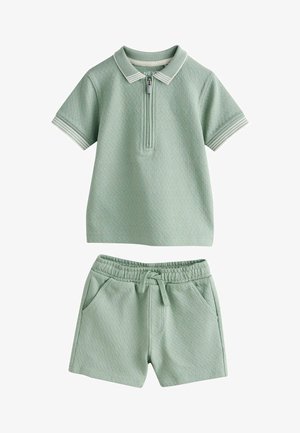 Miękka zielona koszulka polo z krótkim rękawem, z suwakiem przy kołnierzu oraz dopasowane elastyczne szorty w talii z troczkami i bocznymi kieszeniami.