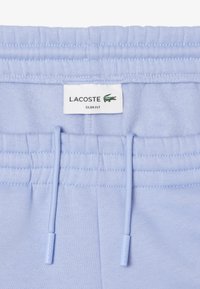 Hellblaue Slim-Fit-Sweatpants mit geripptem Taillenbund, Zugbandverschluss und Lacoste-Logoetikett. Glatte Stoffstruktur.