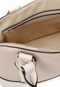 Borsa a tracolla in pelle beige con una texture liscia, hardware dorato e chiusura con zip. L'interno presenta una fodera beige semplice e una tasca piccola.