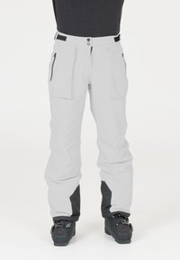 Witte skibroek met zwarte accenten, twee grote voorzakken, ritsdetails en een losse pasvorm, ontworpen voor activiteiten in koude weersomstandigheden.