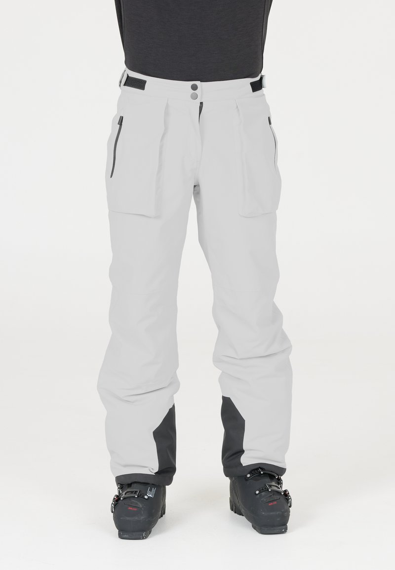 Witte skibroek met zwarte accenten, twee grote voorzakken, ritsdetails en een losse pasvorm, ontworpen voor activiteiten in koude weersomstandigheden.
