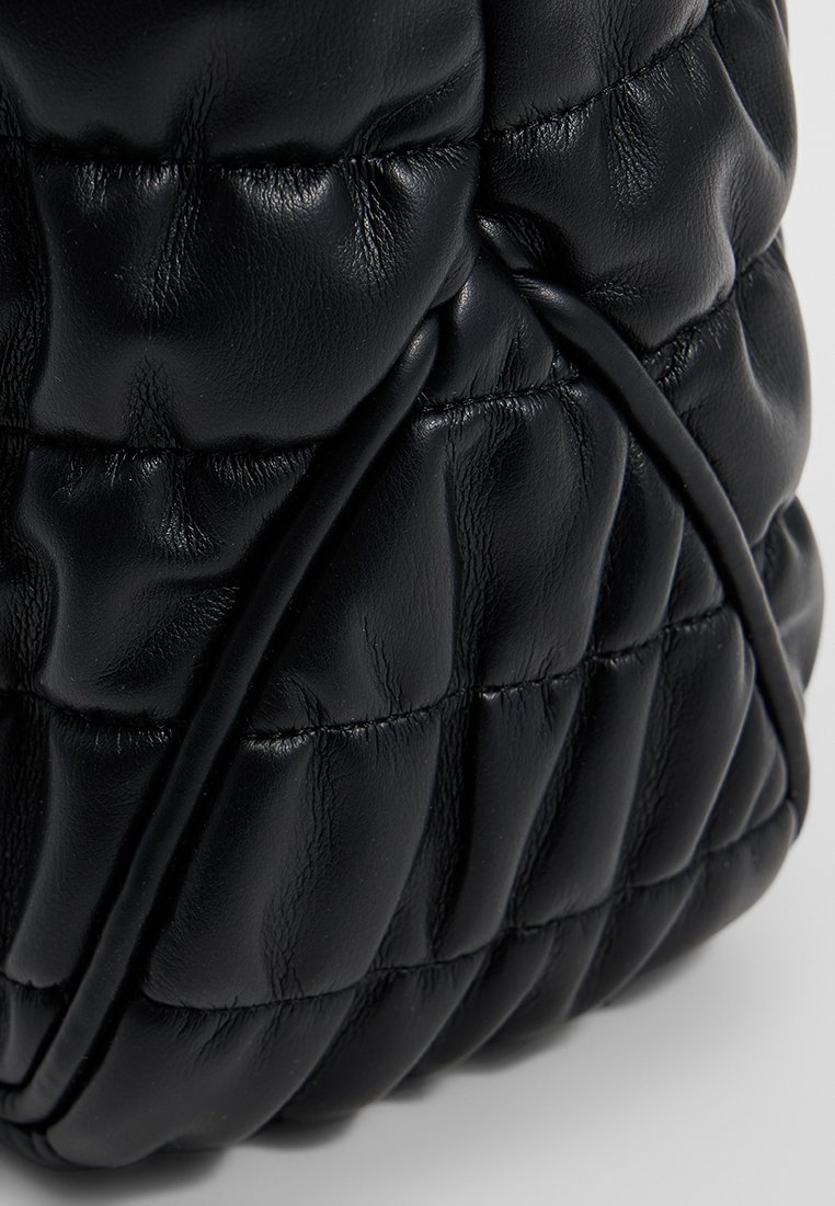 Borsa a tracolla nera in pelle con texture trapuntata, caratterizzata da una forma arrotondata e sottili dettagli elastici lungo le cuciture.