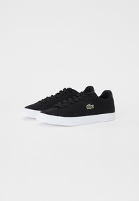 Sneakers in tela nera con suola in gomma bianca, caratterizzate da un logo ricamato verde discreto e lacci neri piatti. Design a profilo basso.