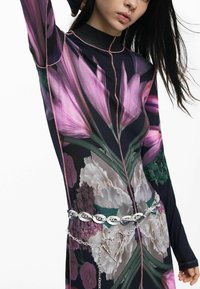 Lillemustriga pikkade varrukatega kleit, millel on lillad ja rohelised toonid. Täiendatud hõbedase kettvöök and südamekujuline detail.