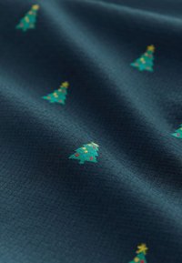 Marineblåt stof med et struktureret mønster, der indeholder små, farverige juletræer pyntet med lys og stjerner.