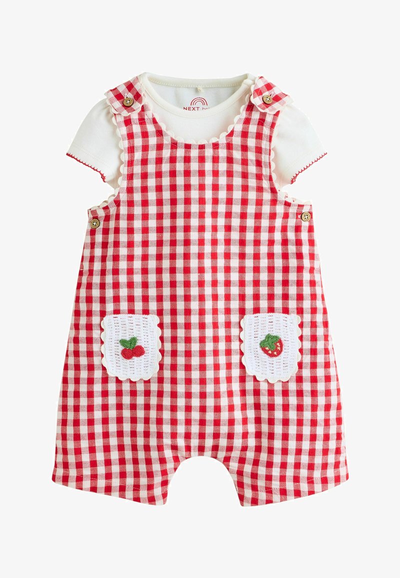 Pelele de bebé a cuadros rojos y blancos con tirantes de botones y bolsillos blancos bordados con cereza y fresa sobre una camiseta blanca de manga corta.