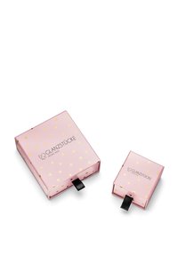 Dve roza škatle z zlatimi detajli, ena večja z črnim povlečnim trakom in logotipom, in ob njej manjša škatla, prav tako s povlečnim trakom.